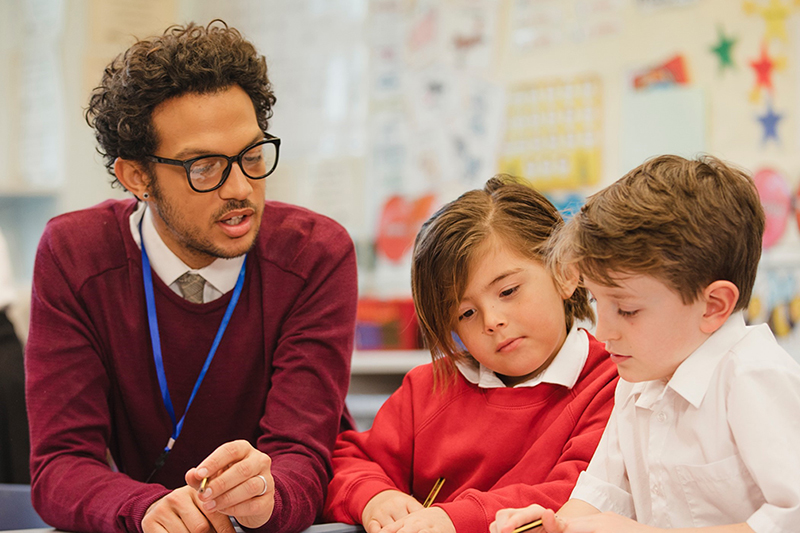 Volunteer talking to two young students