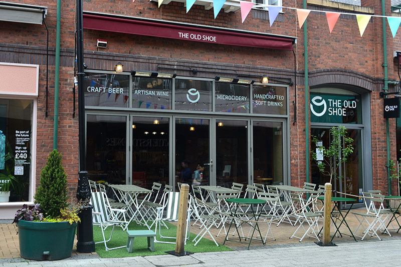 Shop front of The Old Shoe pub with chairs and tables outside