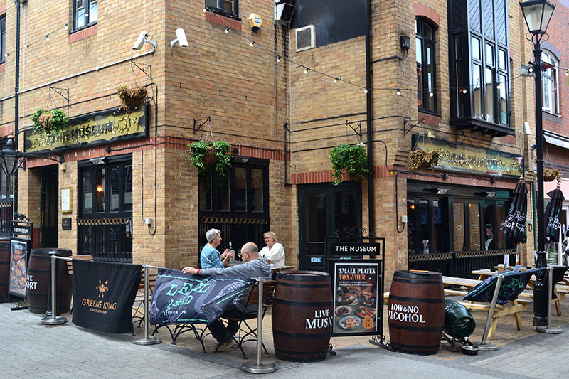 Outdoor seating in front of The Museum pub with customers drinking